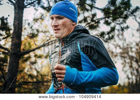 closeup of male runner of middle-aged runs through forest