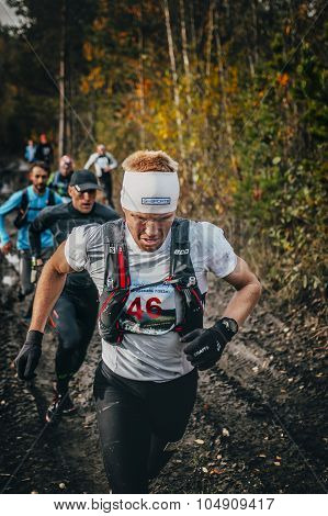 male runners run group on a dirt road in woods
