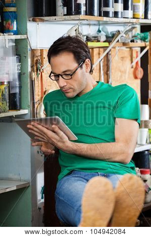 Relaxed worker using digital tablet while sitting in paper factory