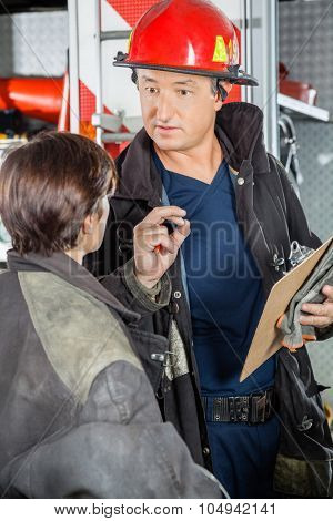 Confident male firefighter discussing with female colleague at fire station