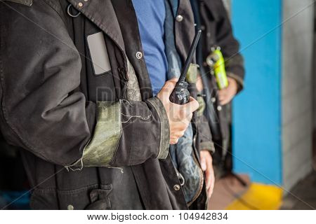 Midsection of fireman holding walkie talkie at fire station