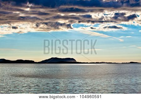 Norwegian Landscape At Sunset With The Sea Water, Cloudy Sky And Fjord Mountain In The Background