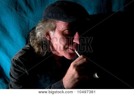 Hombre disfrutando de la pipa de tabaco en cuarto oscuro