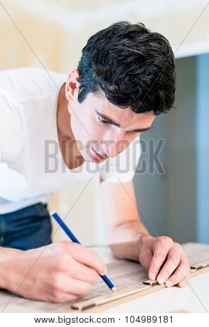 Carpenter measuring wood piece for flooring