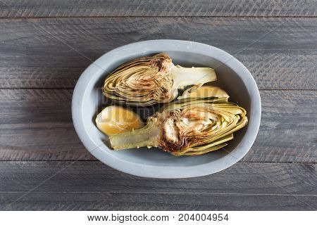 Artichokes and lemons on the plate. This product has one of the highest antioxidant capacities. Traditional vegetables in italian cuisine. Gray wooden background