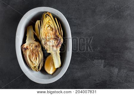 Artichokes and lemons on the plate. This product has one of the highest antioxidant capacities. Traditional vegetables in italian cuisine. Photo contains the copy space