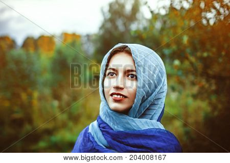 a woman in a scarf stands among the greens