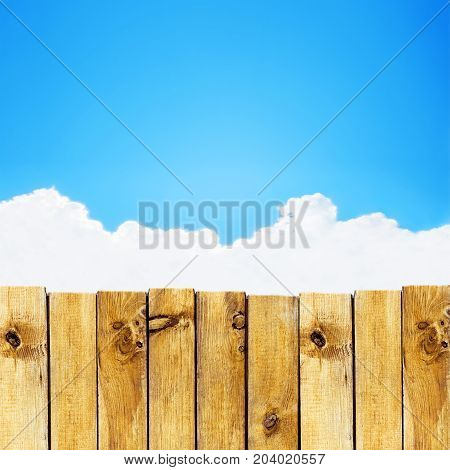 Wooden fence against blue sky with cloud background
