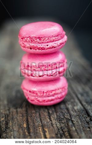 Delicious macarons raspberry flavored with fresh raspberries and a sprig of mint presented on a wooden shelf