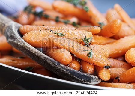 A rustic wooden spoon filled with Honey Glazed Baby carrots. Extreme shallow depth of field with selective focus on foreground.