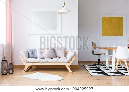 Gold and silver gallery in spacious room with pastel pillows on sofa and dining table on black and white carpet
