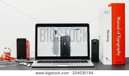 PARIS FRANCE - SEP 3 2017: Minimalist creative room table with Safari Browser open on MacPook Pro laptop showcasing Apple Computers website with latest iPhone X 10 with waterproof capabilities