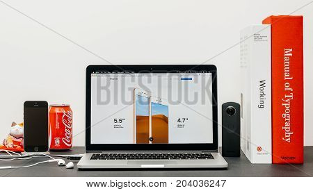 PARIS FRANCE - SEP 13 2017: Minimalist creative room table with Safari Browser open on MacBook Pro laptop showcasing Apple Computers website with latest iPhone 8 and 8 Plus display size inch