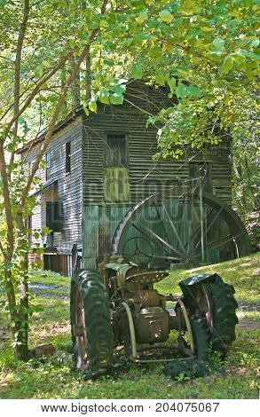 an old gristmill behind a rusty tractor