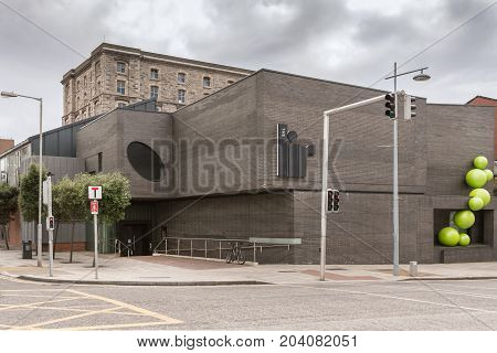 Dublin Ireland - August 7 2017: The brown low LIR Academy sits on a street corner under heavy skies. Older building behind. Street scene with traffic lights.