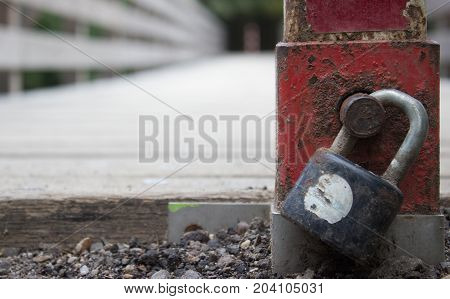 With a lock pad locked across the bridge. Padlock detail. In the background are trees.