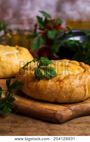 Round meat pie with vegetables and spices on a wooden background. Selective focus.