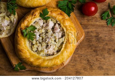 Round meat pie with vegetables and spices on a wooden background. Selective focus.