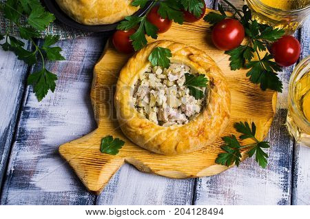 Round meat pie with vegetables and spices on a wooden background. Selective focus.