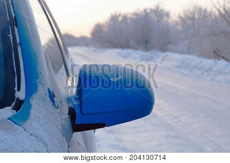 car with outside mirror . Snowy road surface