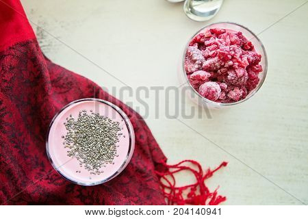 Chia and frozen raspberies cottage cheese breakfast in two small transparent glasses
