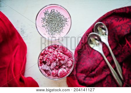 Chia and frozen raspberies cottage cheese breakfast in two small transparent glasses