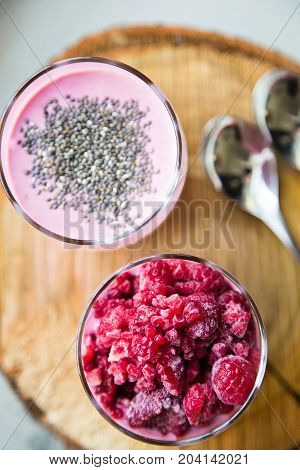 Chia and frozen raspberies cottage cheese breakfast in two small transparent glasses