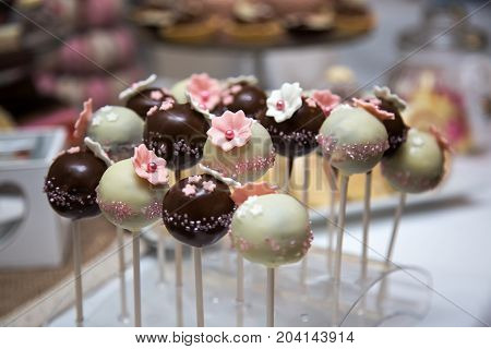 Chocolate cake pops covered in milk and white chocolate decorated with pink edible marzipan flowers