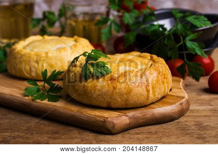 Round meat pie with vegetables and spices on a wooden background. Selective focus.