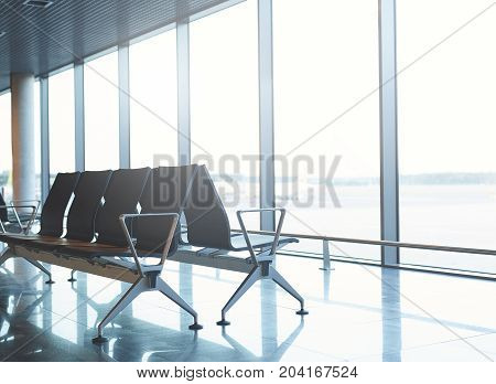 Empty airport terminal waiting area with chairs. passenger seat in Departure lounge for see Airplane, view from airport terminal. transport and travel concept