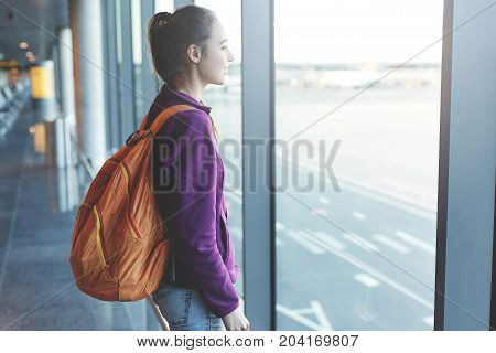 Girl at the airport window looking outside
