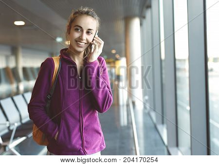 Girl at the airport window talking by phone