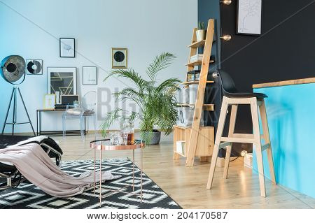 Spacious relax room with barstool at kitchen island and wooden shelf on black wall