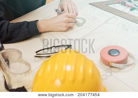 Architect drawing on a blueprint with a compass and ruler.