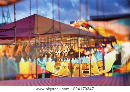 Multicolored light at the fair with evening attractions. Blurry. Tilt-shift lens