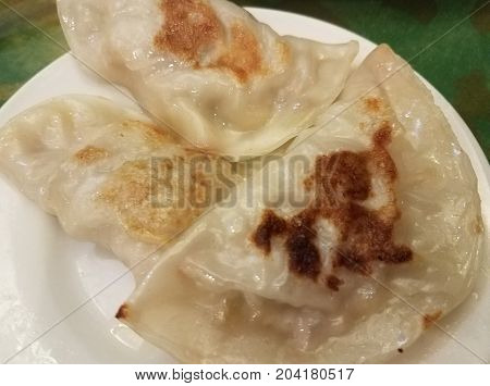 three Chinese potstickers or meat dumplings on a plate