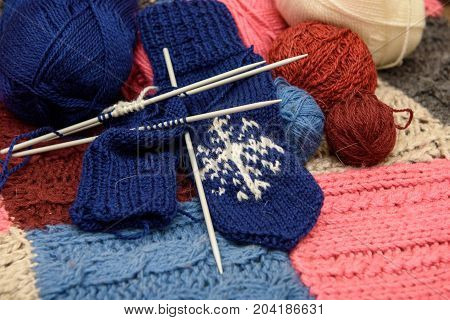 Knitted yarn mittens lie on a woolen blanket.