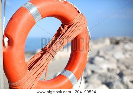 Orange Lifebuoy For People Near Rocks At The Sea