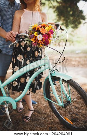 Vertical close-up image of body parts cute girl and boy. with bright gift, standing in the forest with bicycle. Lifestyle concept.
