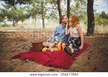 Image of female and manle with bright picnic, sitting in the forest. Lifestyle concept.