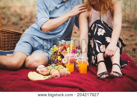 Close-up photo of body parts woman and man. with bright picnic, sitting in the forest. Lifestyle concept.