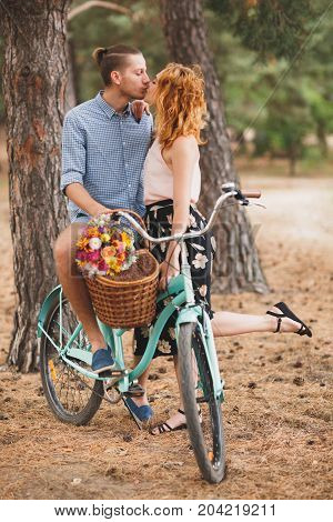 Image of love story in the forest. Beautifull couple kissing and embracing near the shore of a mountain river with decorated table. Girl smiling in the arms.