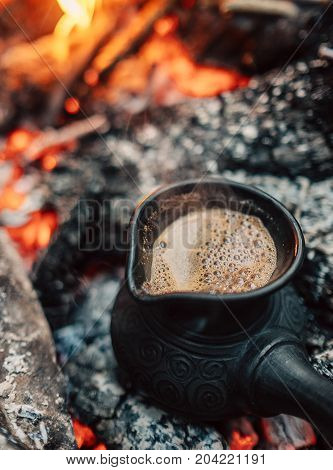 Boil coffee on turkish cezva on campfire coals