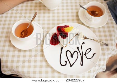 A young couple ordered a cheesecake in a cafe.