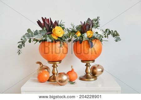 Beautiful autumn floral bouquet in a pumpkin vase. Preparing for Halloween. Table setting for the wedding