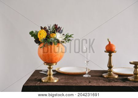 Beautiful autumn floral bouquet in a pumpkin vase. Preparing for Halloween. Table setting for the wedding