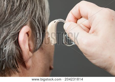 Closeup senior woman with hearing aid in her ear. Health care hear amplify device for the deaf.