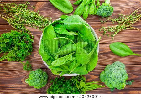 Top View Fresh Spinach Leaves With Water Drops In Ceramic Bowl And Other Green Herbs And Broccoli On