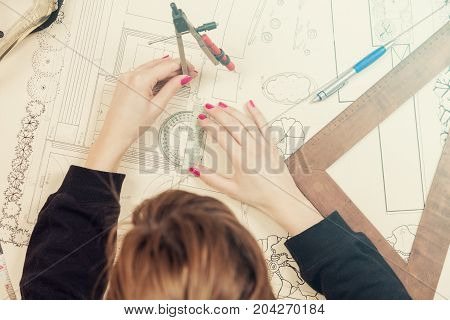 Architect drawing on a blueprint with a compass and ruler.