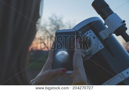 Photographing the Moon through a telescope with cellphone.